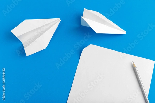 Fototapeta Flat lay of a paper plane on pastel blue color background