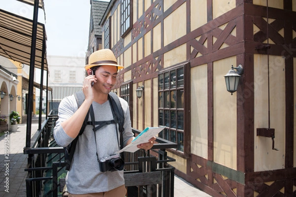Obraz Asian traveler take smartphone for asking location to fine some location from map in hand