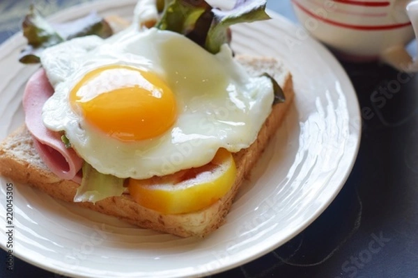 Fototapeta sandwich runny sunny side up egg ham with black coffee and glasses on blackboard background, brain boost breakfast concept