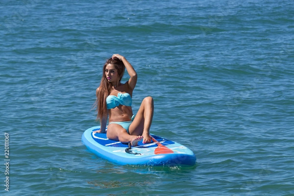 Fototapeta Woman relaxing on a SUP boarding in the sea. Healthy lifestyle in harmony with nature.