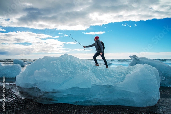Fototapeta Tourist man taking selfie on small iceberg Located in Diamond beach near Jokulsarlon Lagoon, Iceland