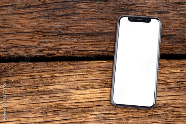 Fototapeta Smartphone lies on a wooden table. Isolated white screen with copy space.