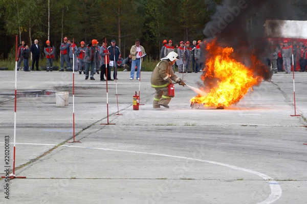 Fototapeta Competitions firefighters. The fireman works with a fire extinguisher to extinguish the fire.