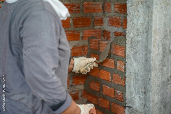Fototapeta Close up of industrial bricklayer installing bricks on construction site in thailand
