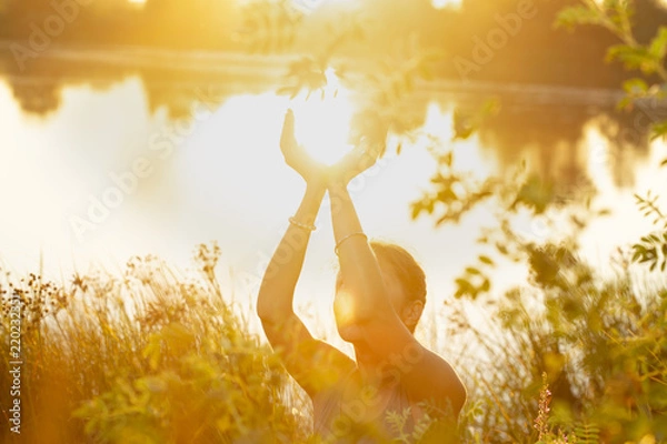 Fototapeta woman hands in mudra like in the palm of hands, at sunset  on the lake in nature