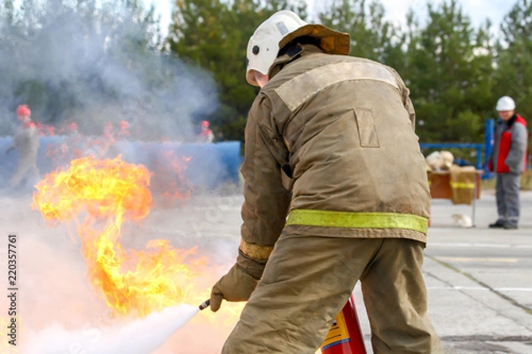 Obraz Competitions firefighters. The fireman works with a fire extinguisher to extinguish the fire...
