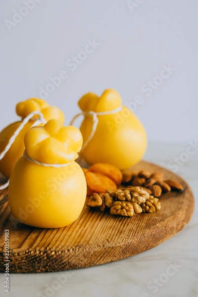 Fototapeta Scamorza cheese with walnuts, almonds and dried apricots on a wooden board, marble background, copy space.