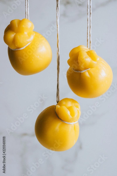 Fototapeta Scamorza cheeses are hanged together in strings to ripen on marble background