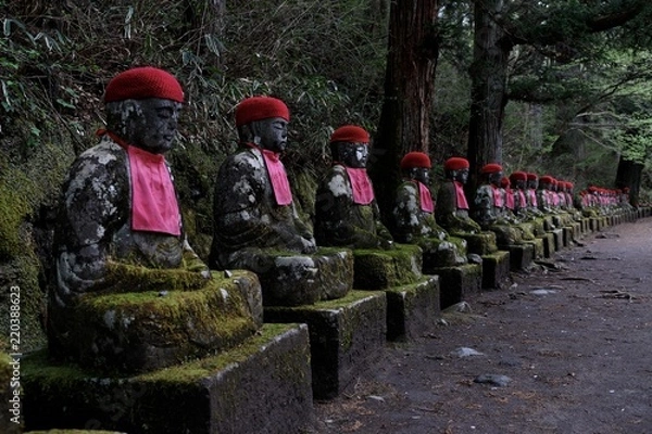 Obraz Nikkos steinerne Buddhas mit roter Strickmütze