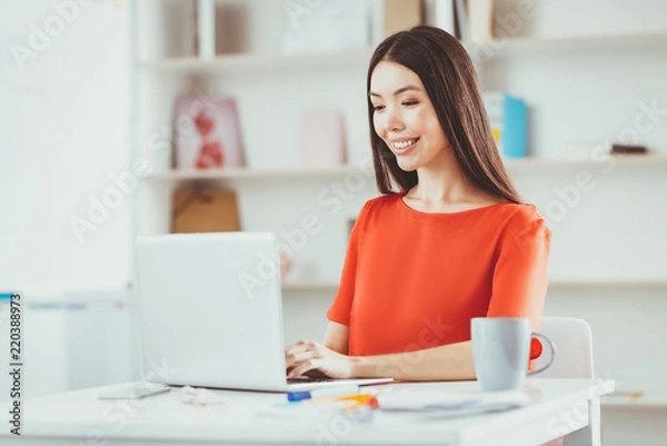 Fototapeta Distance work. Joyful happy woman typing the text while working remotely