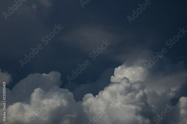 Fototapeta white cumulus clouds on dark blue sky in shadows