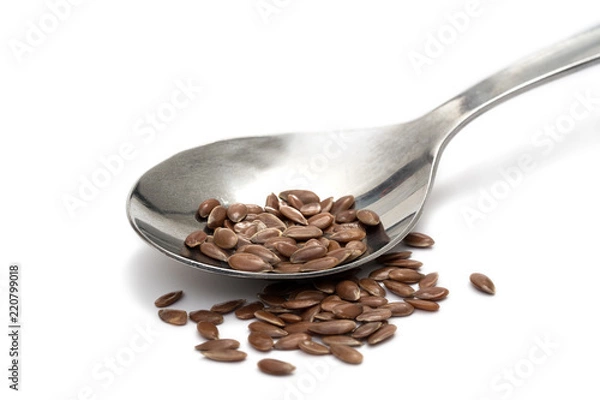 Fototapeta Close up of linseeds or flax seeds on a metal teaspoon isolated on white background