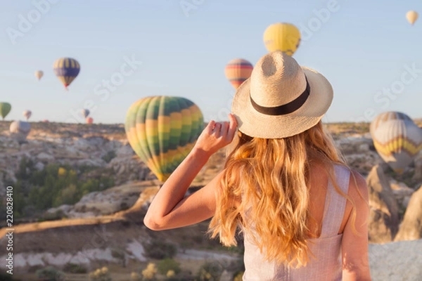 Fototapeta Hipster Traveler with backpack and outspread hands. Enjoying the view of the hot air balloons