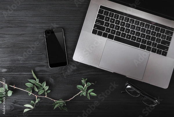 Fototapeta Modern workspace with notebook or laptop, smartphone and eyeglasses on wood texture background. Top view, flat lay style