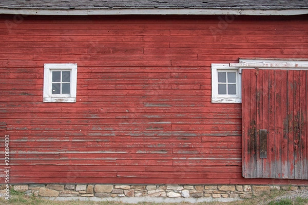 Fototapeta Side of an old red barn with white framed square windows and sliding door