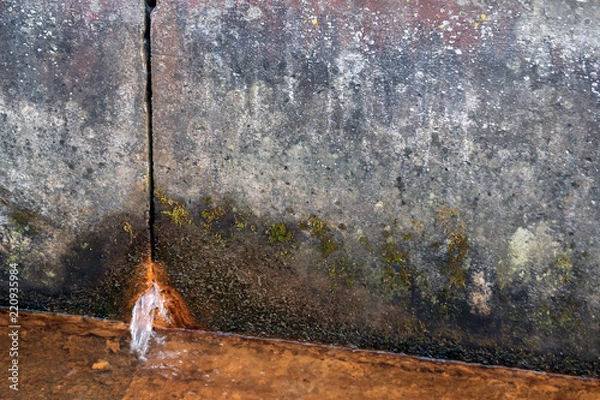 Fototapeta two concrete slabs of dirty gray color in spots, rusty water flows from the hole from below, in the foreground there is a liquid rusty from corrosion, a gloomy look, design, background, daylight,