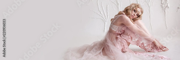 Fototapeta Delicate portrait of a young model girl. The image of the bride, a light lace dress in pink, a beautiful hairstyle and a natural make-up. Light photo studio, natural light from the window.