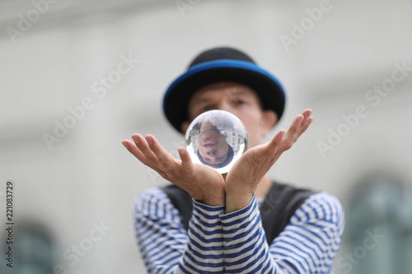 Fototapeta Transparent magic ball with reflection in the open palms of the clown