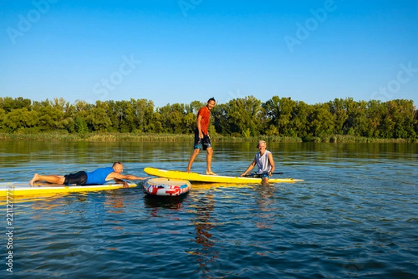 Obraz Joyful friends, a SUP surfers relax on the big river