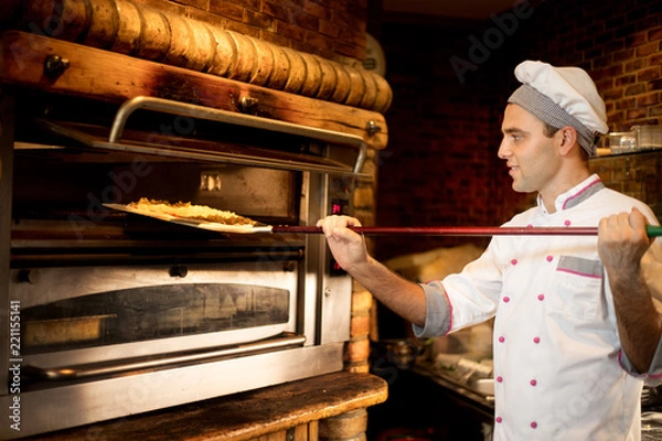 Obraz Chef prepares pizza in the oven