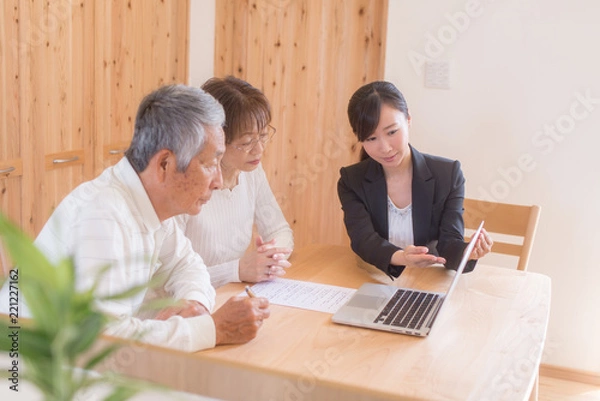 Obraz スーツの女性からパソコンで説明を受けるシニア夫婦