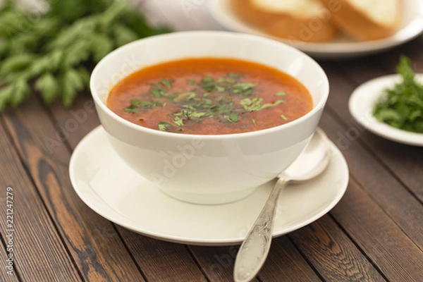 Fototapeta Chicken soup with vegetables and herbs in a white bowl on a wooden table