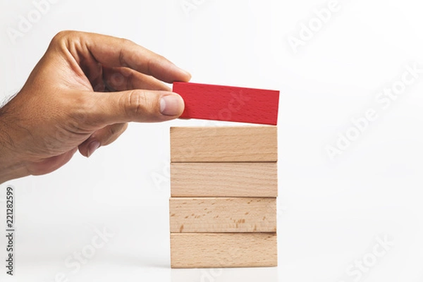 Fototapeta Hand put red wooden block on the stack of wooden blocks