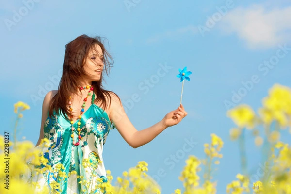 Obraz woman on rape(canola) field with hand mill over blue sky