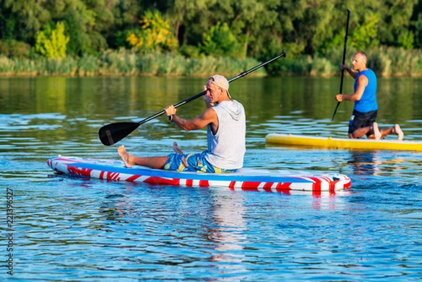 Obraz Happy friends relax on a SUP boards on large river
