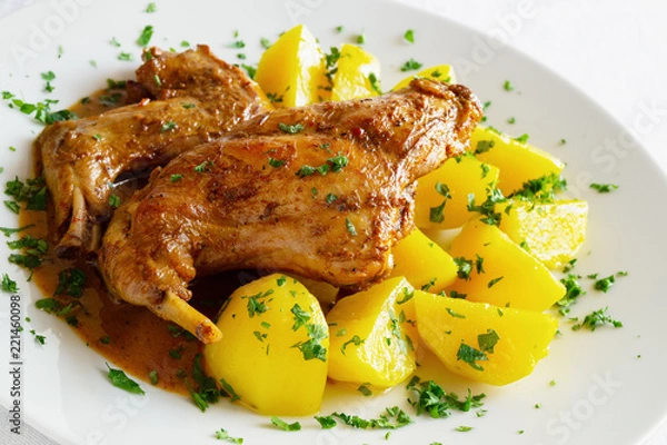 Fototapeta stewed in white wine with herbs and spices marinated rabbit legs on potato sprinkled with parsley