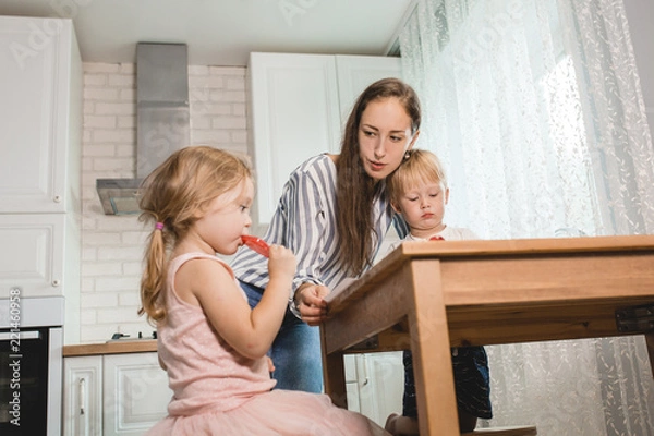 Fototapeta family smiling happily sitting together in the kitchen working and doing their children's homework. Family spending time together in kitchen
