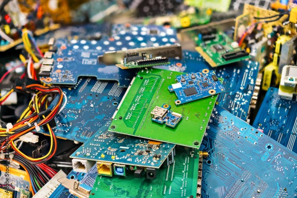 Fototapeta E-waste heap from discarded laptop parts. Connectors, PCB, notebook cards. Colorful blurry background from PC components. Idea of electronics industry, eco, sorting and disposal of electronic waste.
