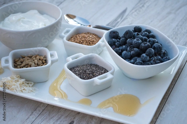 Fototapeta Healthy Breakfast Choice Ingredients-Greek Yogurt with fruit, flax seeds, sunflower seeds, chia seeds and honey