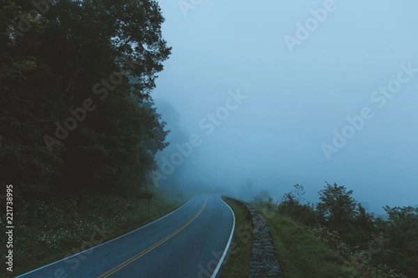 Fototapeta A windy road fades off into the distance in Shenandoah National Park, VA as it's engulfed by clouds.