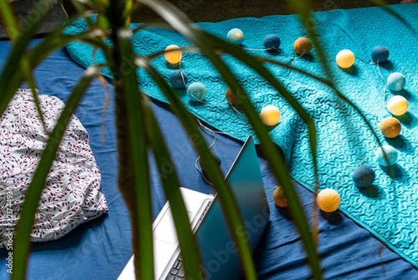 Fototapeta Grey Laptot Laying on Mattress with Turquoise Cover, Few Pillows and a White Background