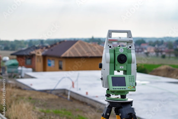 Fototapeta Surveyor measuring equipment (theodolit) on construction site with house in background
