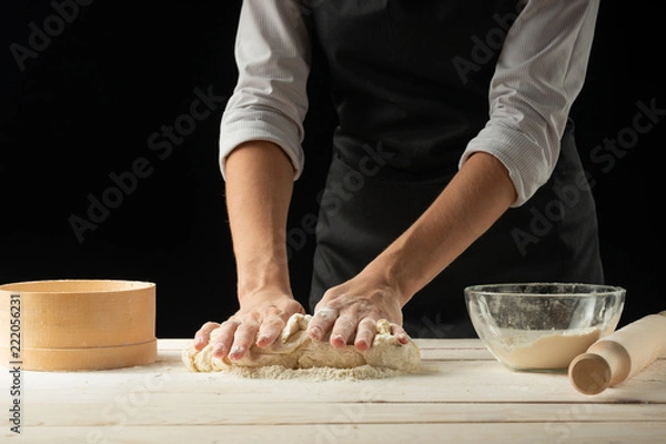Obraz Bakery. Man preparing bread, Easter cake, Easter bread or cross-buns on wooden table in a bakery close up. Man preparing bread dough.