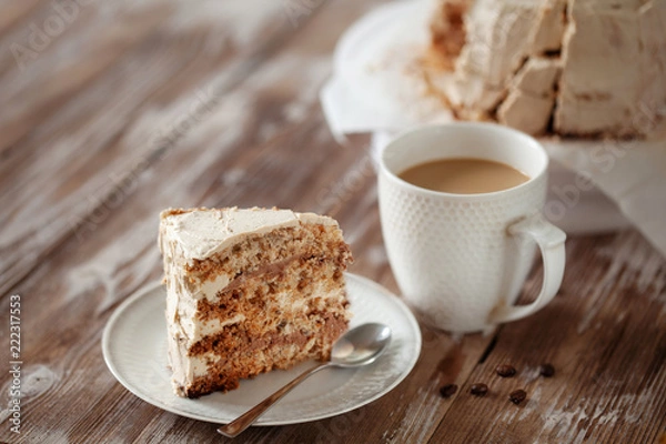 Fototapeta ePiece of crispy coffee and nut meringue cake with butter cream frosting