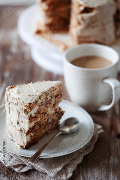 Fototapeta ePiece of crispy coffee and nut meringue cake with butter cream frosting