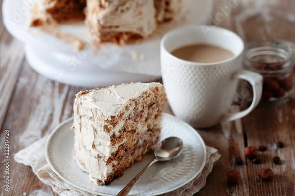 Fototapeta ePiece of crispy coffee and nut meringue cake with butter cream frosting