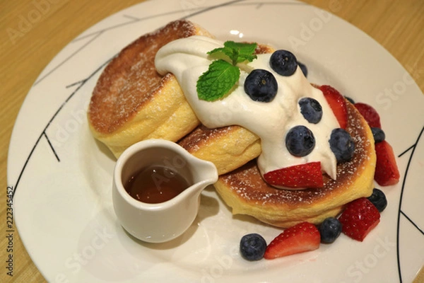 Fototapeta Delicious Souffle Pancake with Maple Syrup, Fresh Whipped Cream and Mix Berries Served on white Plate 