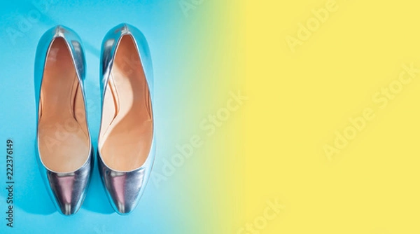 Fototapeta Banner Fashionable women's shoes in silver on a blue yellow gradient saturated background Top view copy space flat layer