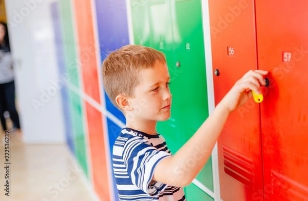 Fototapeta Child boy opening metal school locker.