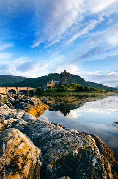 Fototapeta Tourists favourite place in Scotland - Isle of Skye. Very famous castle in Scotland called Eilean Donan castle.  Top of the mountains.Scottish Highlands. Castle with reflection in the lake.