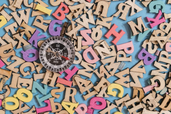 Obraz multicolored wooden letters of the English alphabet on a blue background and compass. Concept search words and search for purpose in life