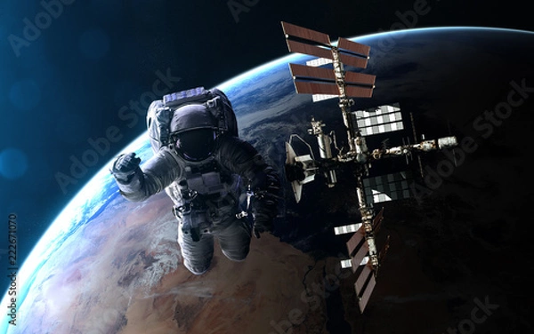 Fototapeta Astronaut and ISS on background of Earth in blue rays of Sun. Abstract science fiction. Elements of the image are furnished by NASA