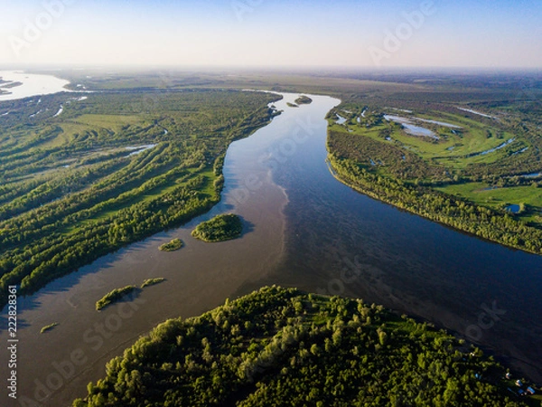 Fototapeta Ob river flows through the taiga. River landscape, beautiful sky reflection in water. Vasyugan Swamp from aerial view. Tomsk region, Siberia, Russia