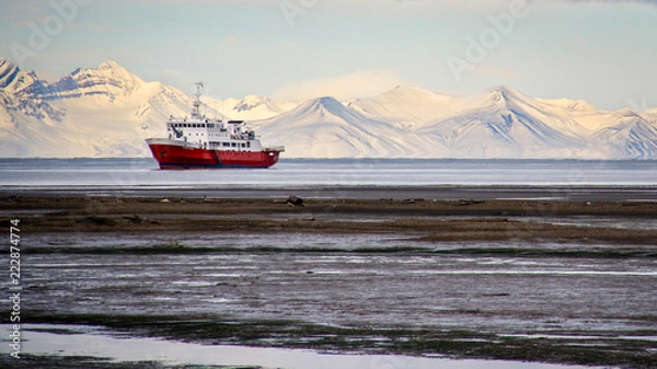 Fototapeta An icebreaker ship sits offshore in front of snow-covered mountains in Longyearbyen, Svalbard, Norwegian Arctic