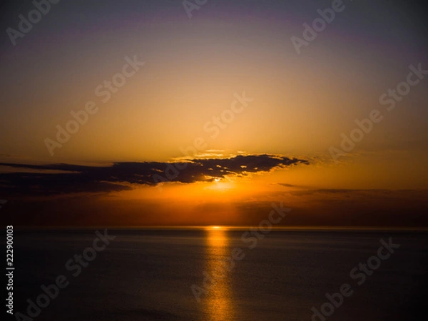 Fototapeta Beautiful sunrise photograph with vibrant orange and yellow colors over the dark waters of Lake Michigan in Chicago with layers of clouds in the sky above.
