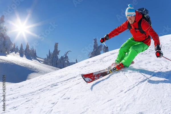 Obraz Skier skiing downhill in high mountains against blue sky